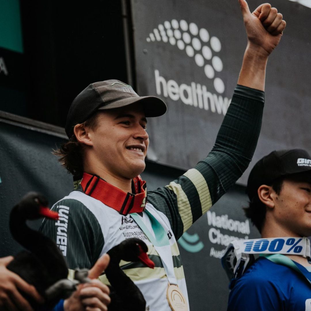 Bailey Christie celebrating on the podium with a medal after an enduro race.